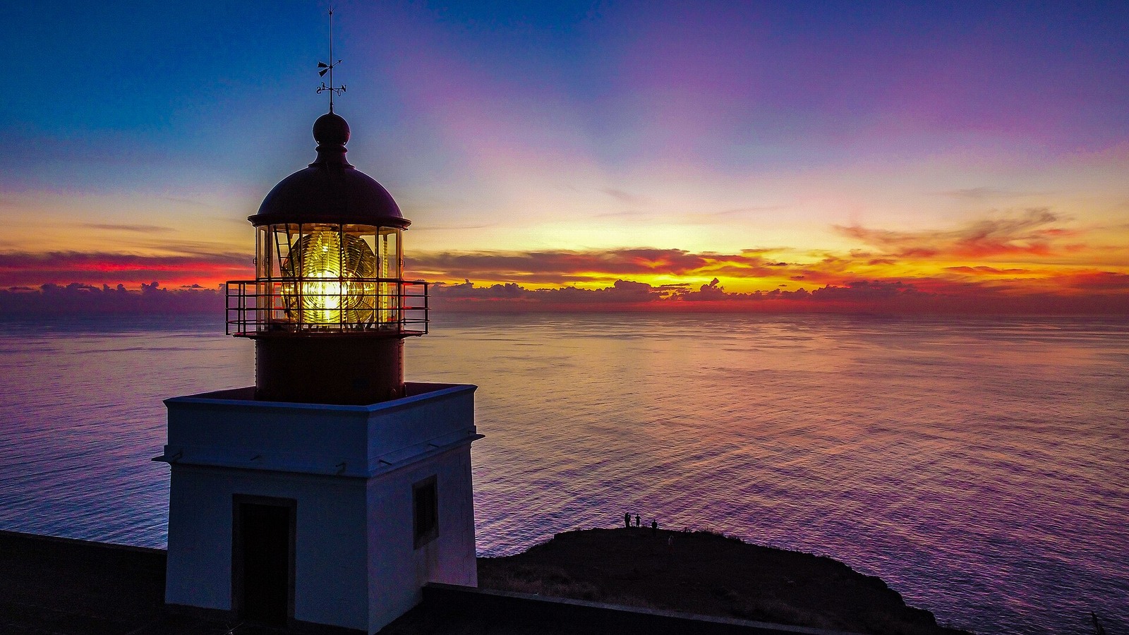 Ponta do Pargo lighthouse glowing above a rocky Atlantic promontory at sunset.